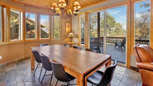 Un comedor amplio con una mesa y sillas de madera, ventanas grandes y vistas al exterior.