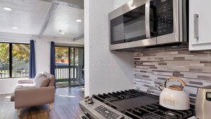Una cucina moderna con un piano cottura in acciaio inossidabile, un bollitore e un forno a microonde.