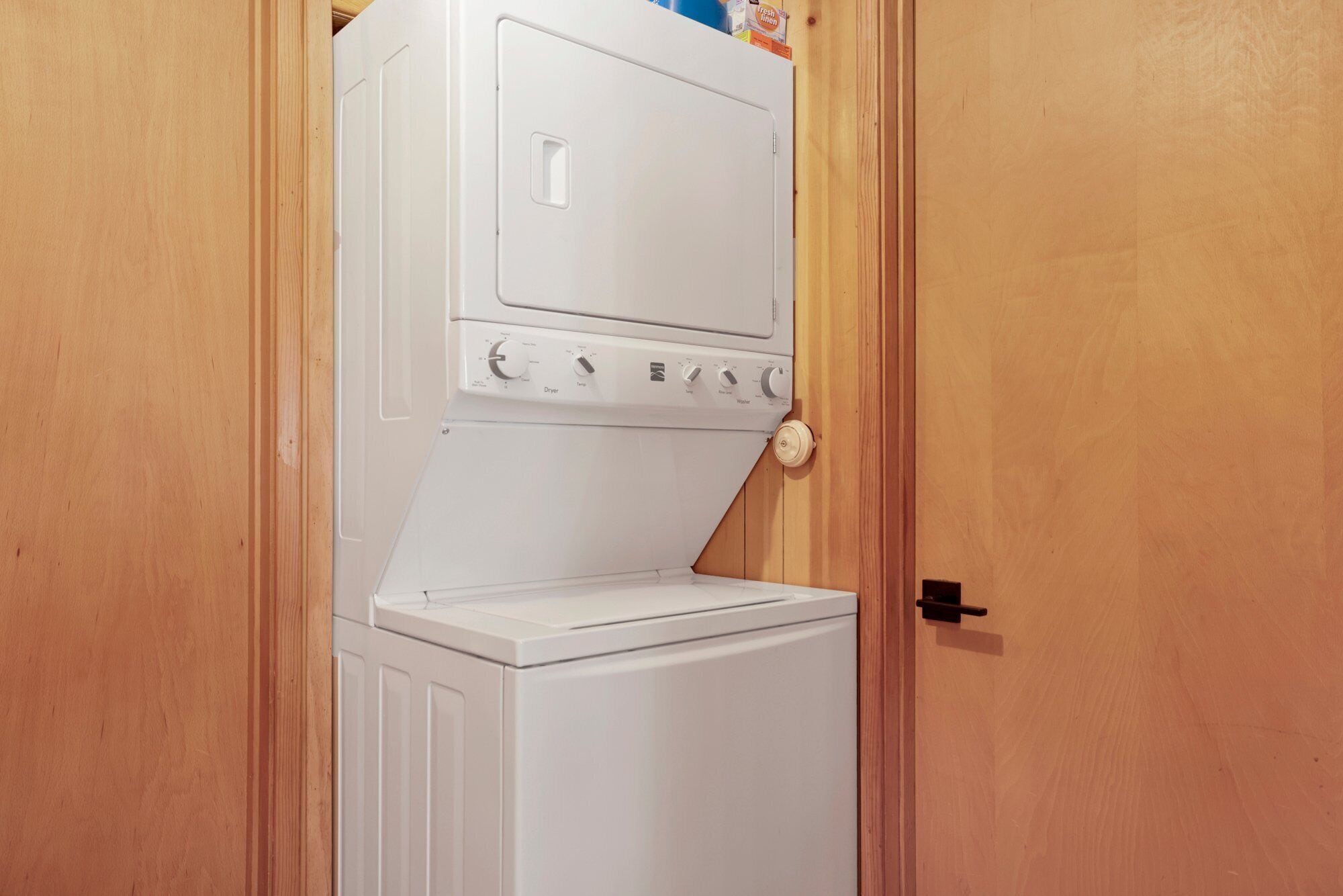 Un lave-linge et un sèche-linge blancs, installés dans un placard en bois.