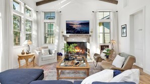 A spacious living room with a fireplace, comfortable seating, and large windows. - Pine Meadow Village Castle #2301 (Big Bear Lake)