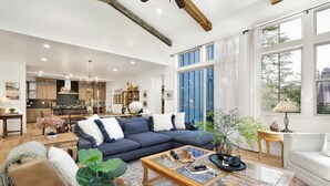 A spacious living room with a large sectional sofa, a glass coffee table, and a view of the kitchen and dining area. - Pine Meadow Village Castle #2301 (Big Bear Lake)