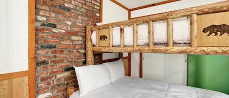 Un lit superposé avec une tête de lit en bois, un mur en briques et une porte verte.