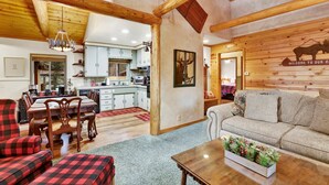 Interior acolhedor de uma cabana com sala de jantar, cozinha e sala de estar.