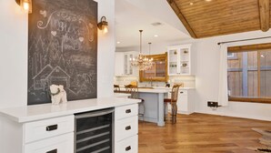 A spacious kitchen with white cabinets, a chalkboard wall, and a wooden ceiling. - Alpine Chalet #1840 (Big Bear Lake)