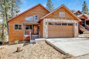 A log cabin with a stone garage, a covered porch, and a staircase leading to the entrance. - Alpine Chalet #1840 (Big Bear Lake)