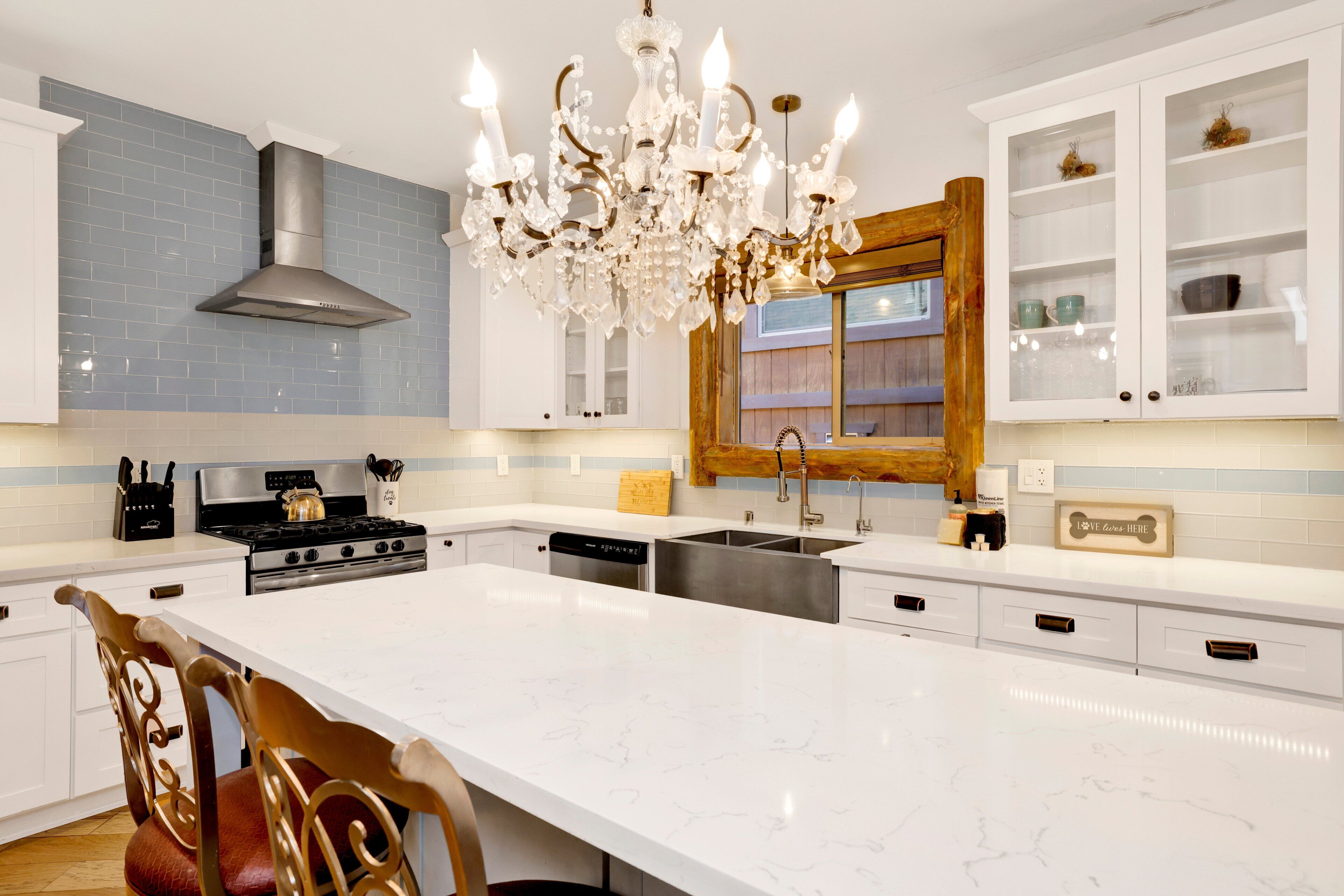 Una cocina moderna con una isla central, electrodomésticos de acero inoxidable y una lámpara decorativa.