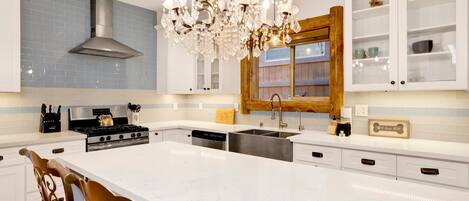 Una cocina moderna con una isla central, electrodomésticos de acero inoxidable y una lámpara decorativa.