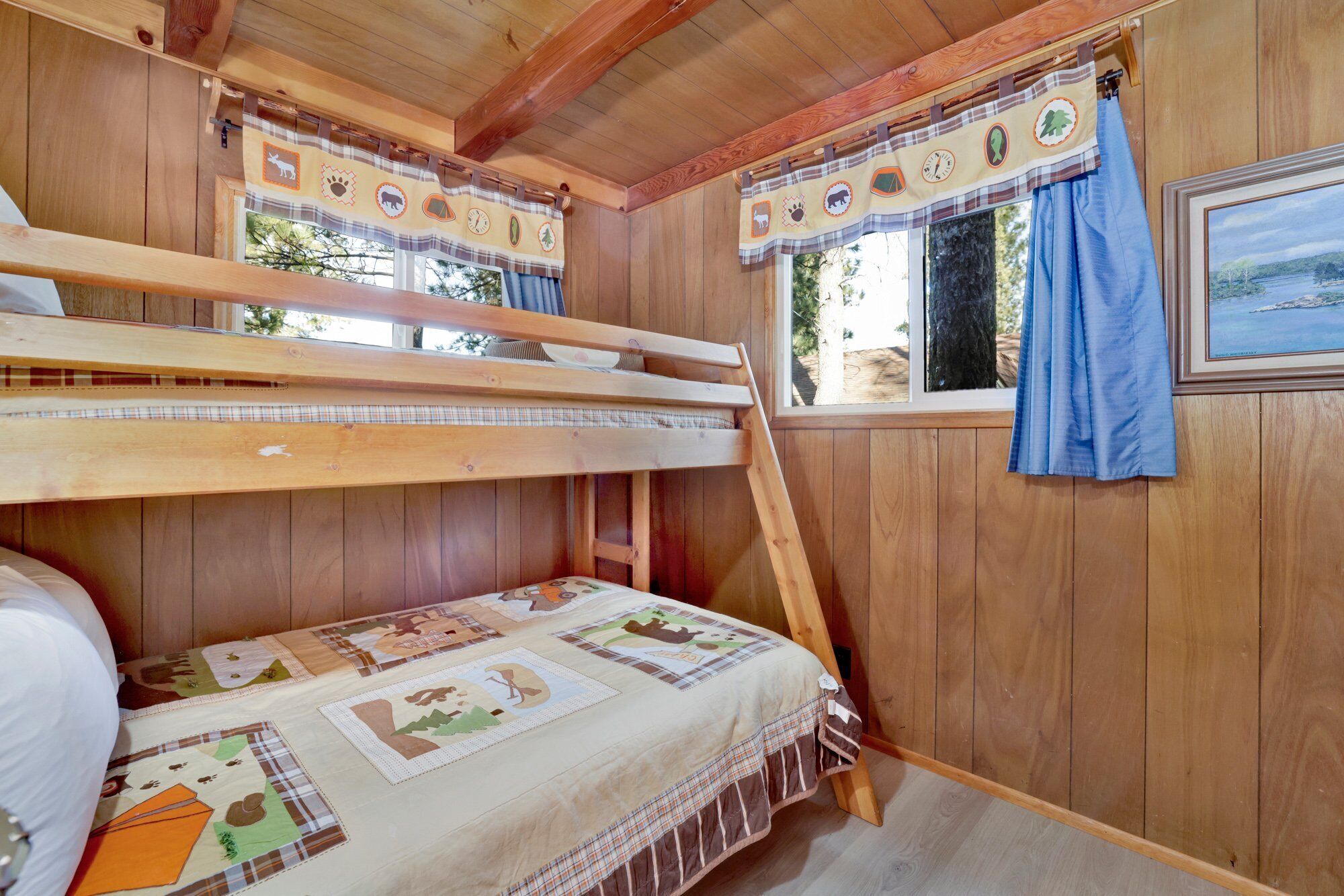Eine Holzhütte mit Etagenbett, einem Fenster mit Aussicht und einem Vorhang mit Tiermotiven.