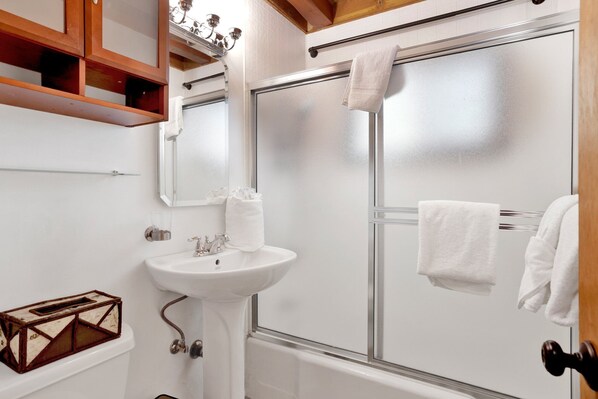 A bathroom with a white sink, a mirror, a shower with a glass door, and a towel rack. - Kozy Cabin #2386 (Big Bear Lake)