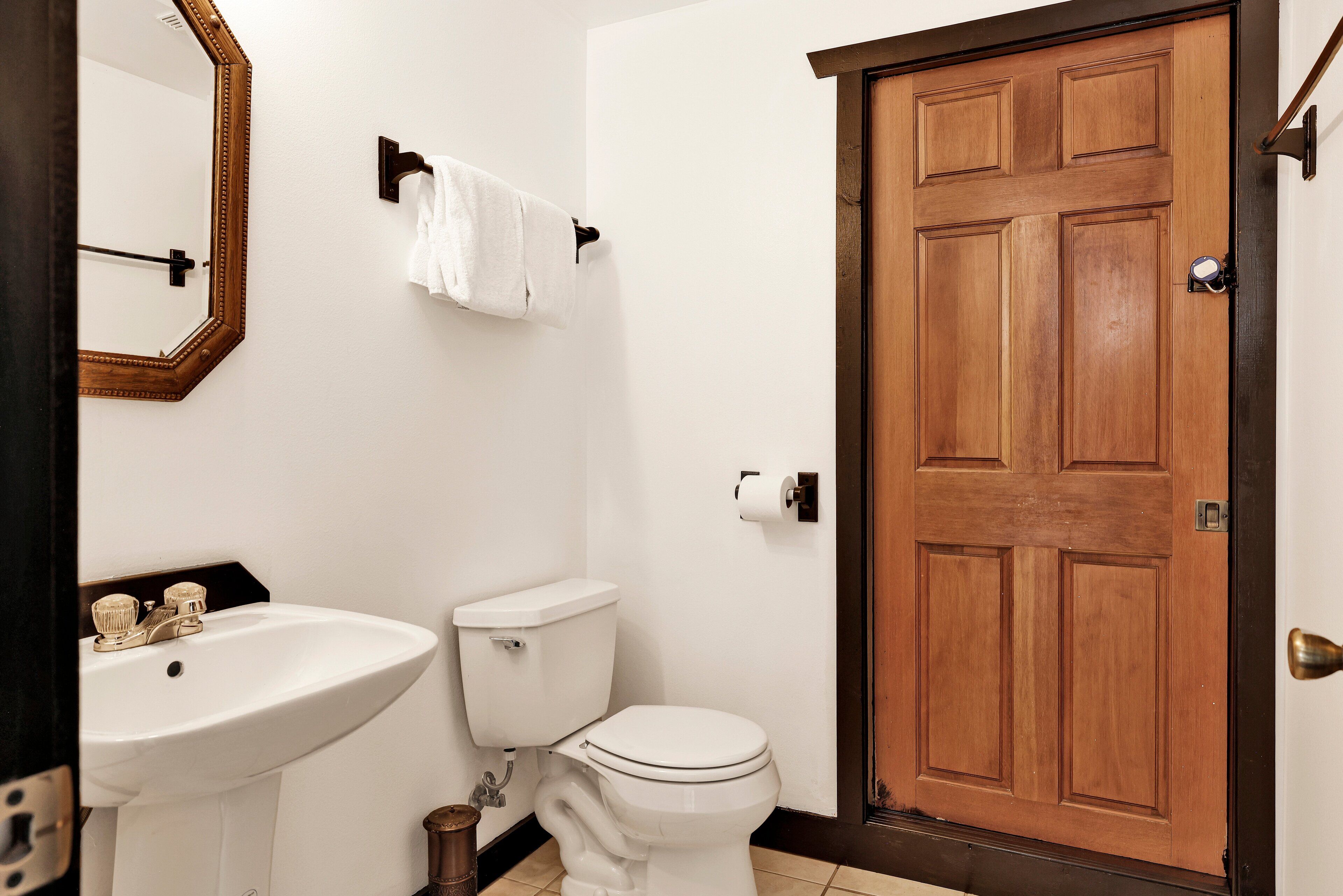 Ein Badezimmer mit Holztür, Waschbecken in Weiß und Toilette.