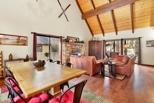 A spacious living area with a wooden dining table, leather sofa, and stone fireplace.