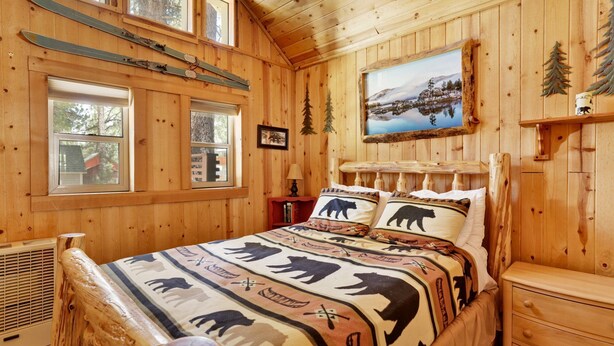 A wooden cabin room with a bed, a window, a painting, and a ski rack. - Moonridge R N R #2320 (Big Bear Lake)