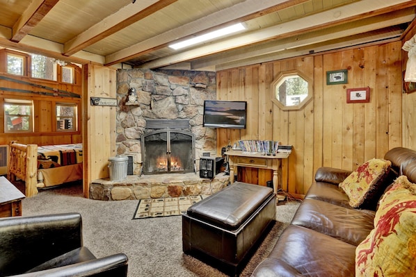 A cozy cabin interior with a stone fireplace, wooden walls, a television, and a comfortable seating area. - Moonridge R N R #2320 (Big Bear Lake)