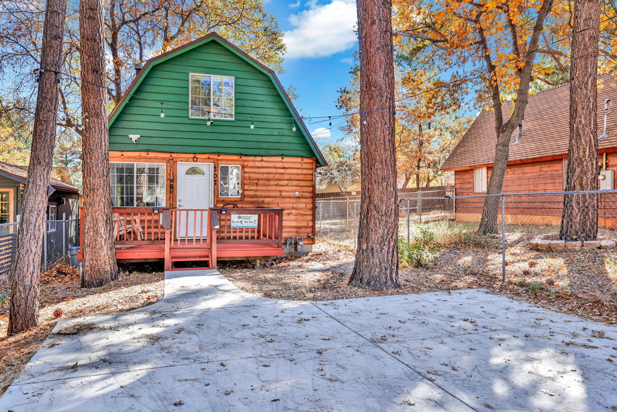 A green log cabin with a porch and a mailbox.