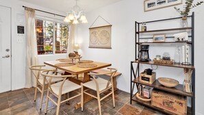 A cozy dining area with a wooden table and chairs, a coffee station, and a bookshelf with various items. - Apres Chalet #2364 (Sugarloaf)