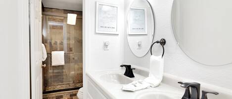 Un baño moderno con un espejo grande, dos lavamanos y una zona de ducha.