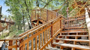 Wooden outdoor stairs with railings, surrounded by trees. - Black OAK Cabin #1977 (Big Bear City)