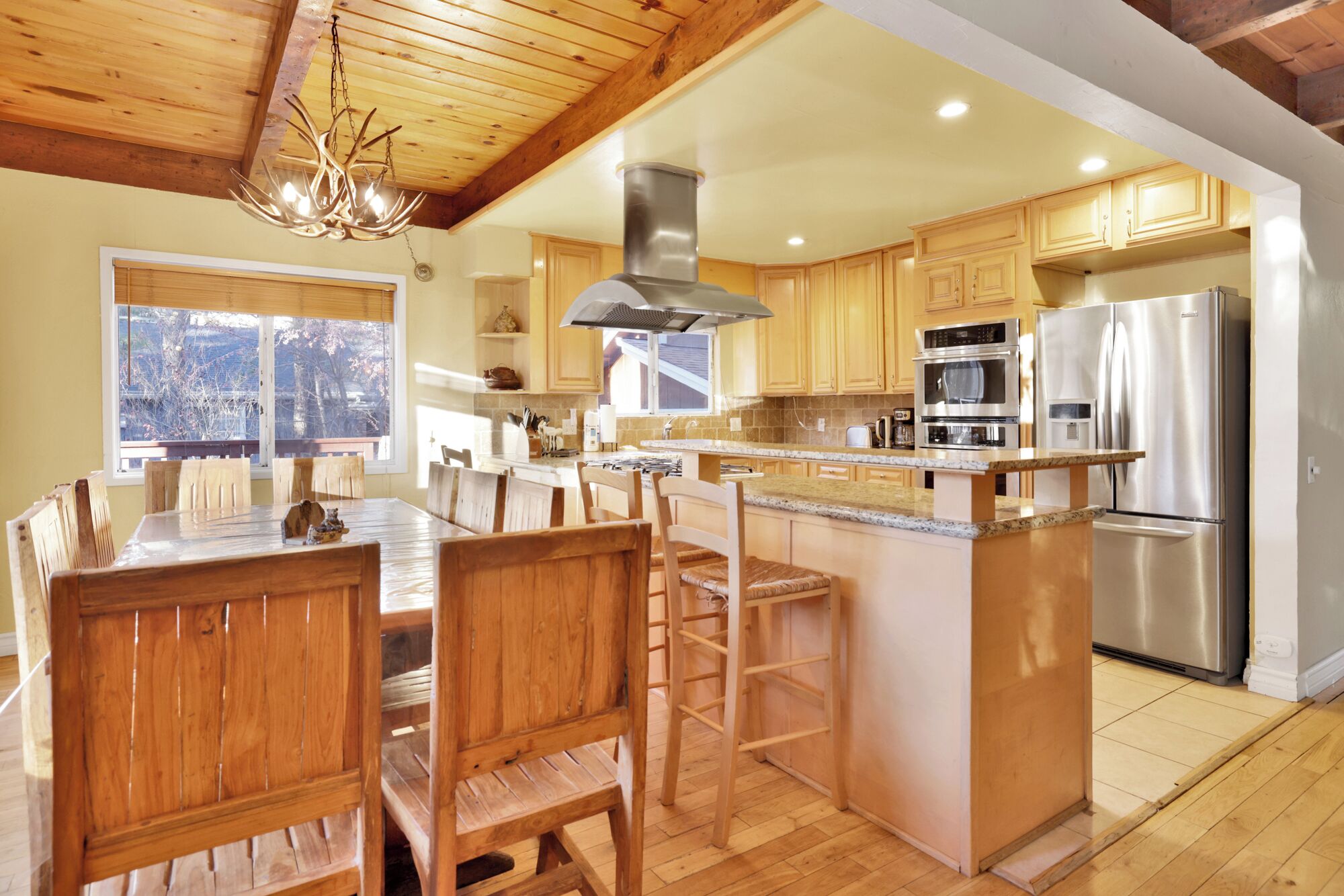 Una cocina moderna con armarios de madera, electrodomésticos de acero inoxidable y una isla grande con taburetes de bar.