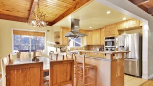 Une cuisine moderne avec des meubles en bois, des appareils en acier inoxydable et un grand îlot central doté de tabourets de bar.