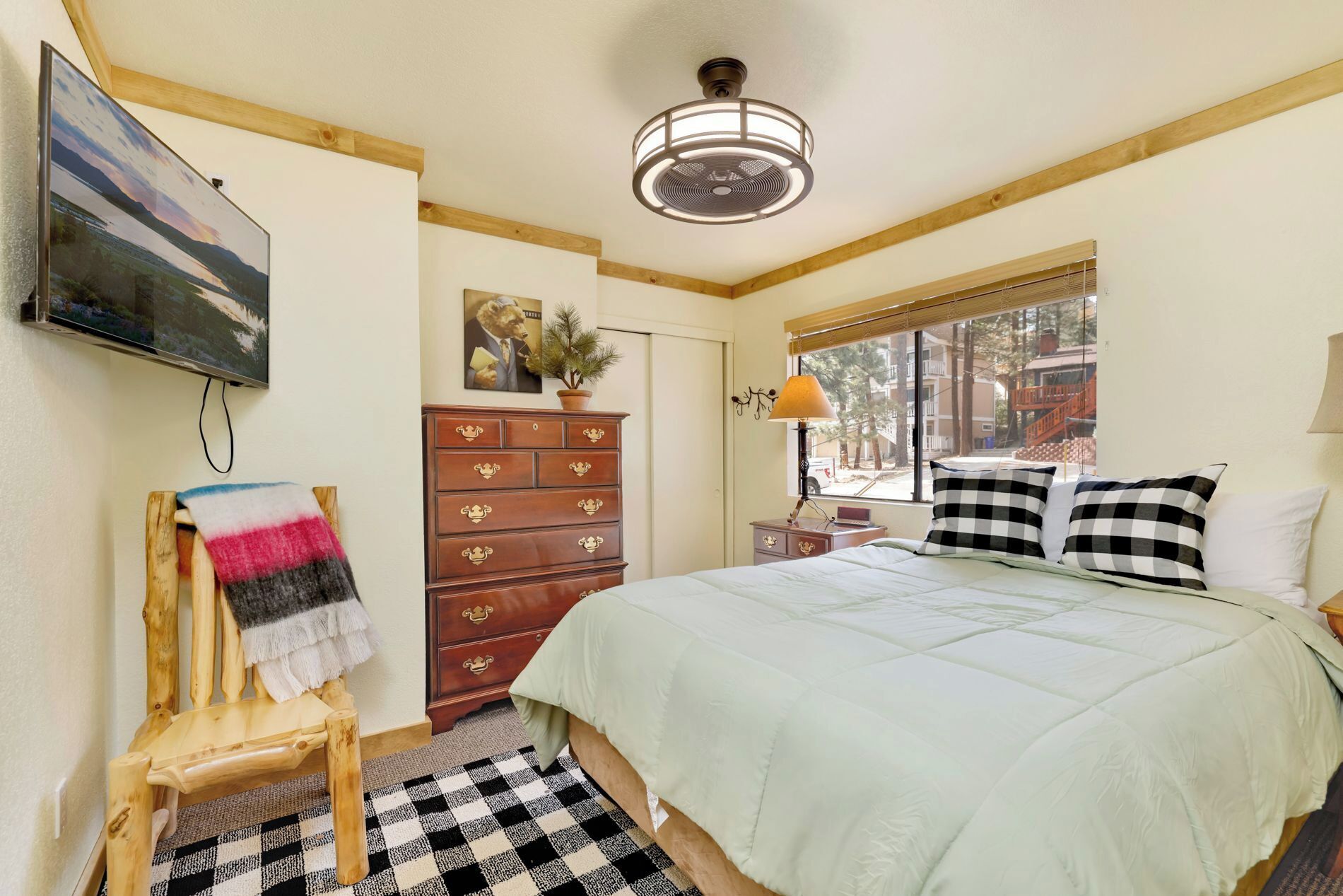 A bedroom with a bed, dresser, lamp, and a painting on the wall.
