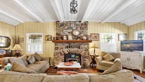 A cozy living room with a stone fireplace, two sofas, a coffee table, and a television. - THE Winding Lane House EST 1932 #2360 (Big Bear City)