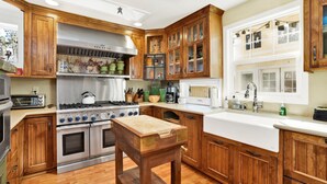 A kitchen with wooden cabinets, a gas stove, a microwave, and a sink. - THE Winding Lane House EST 1932 #2360 (Big Bear City)