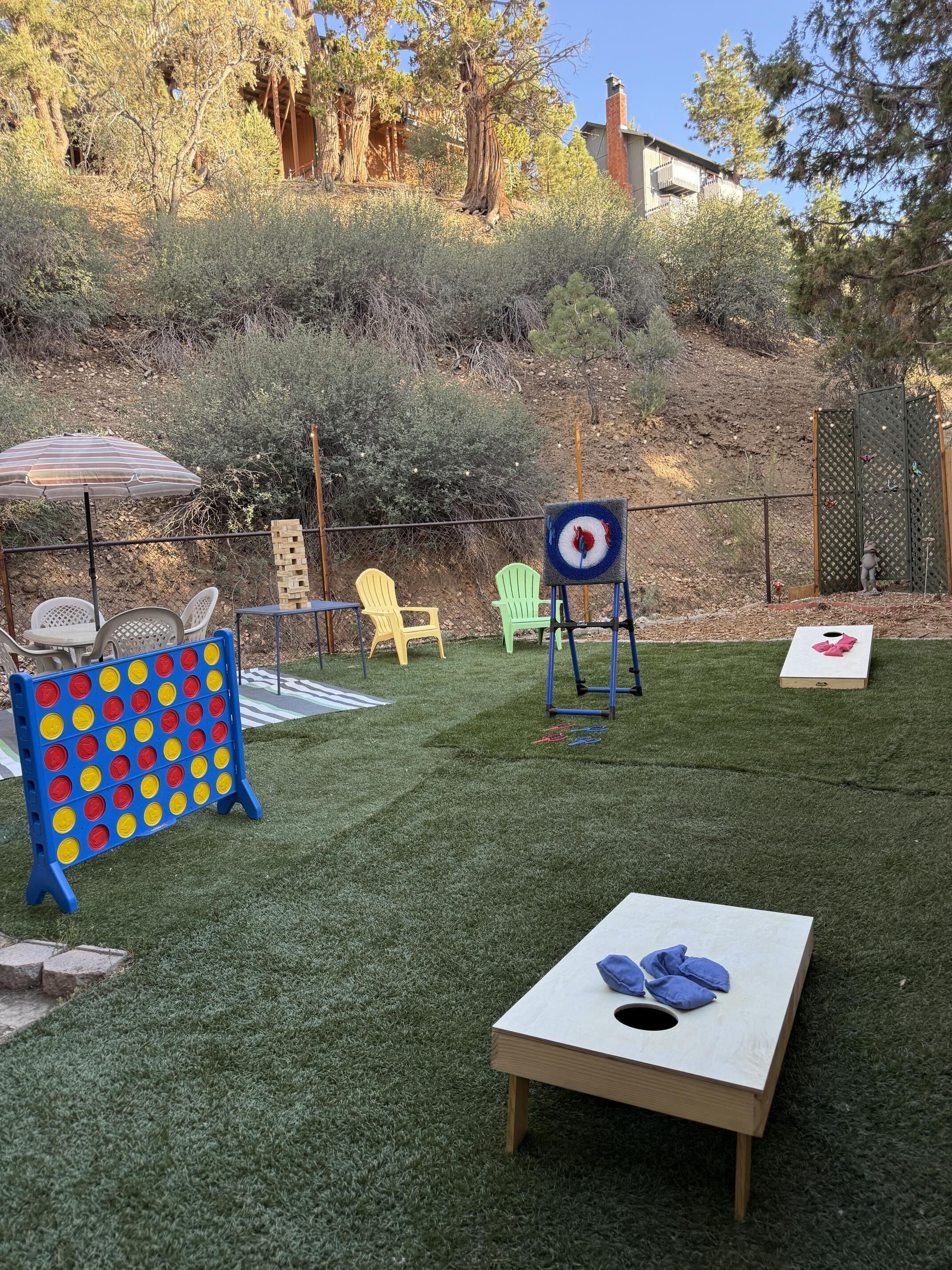 Ein Garten mit einem Gesellschaftsspiel, Stühlen, einer Zielscheibe und einem kleinen Tisch.