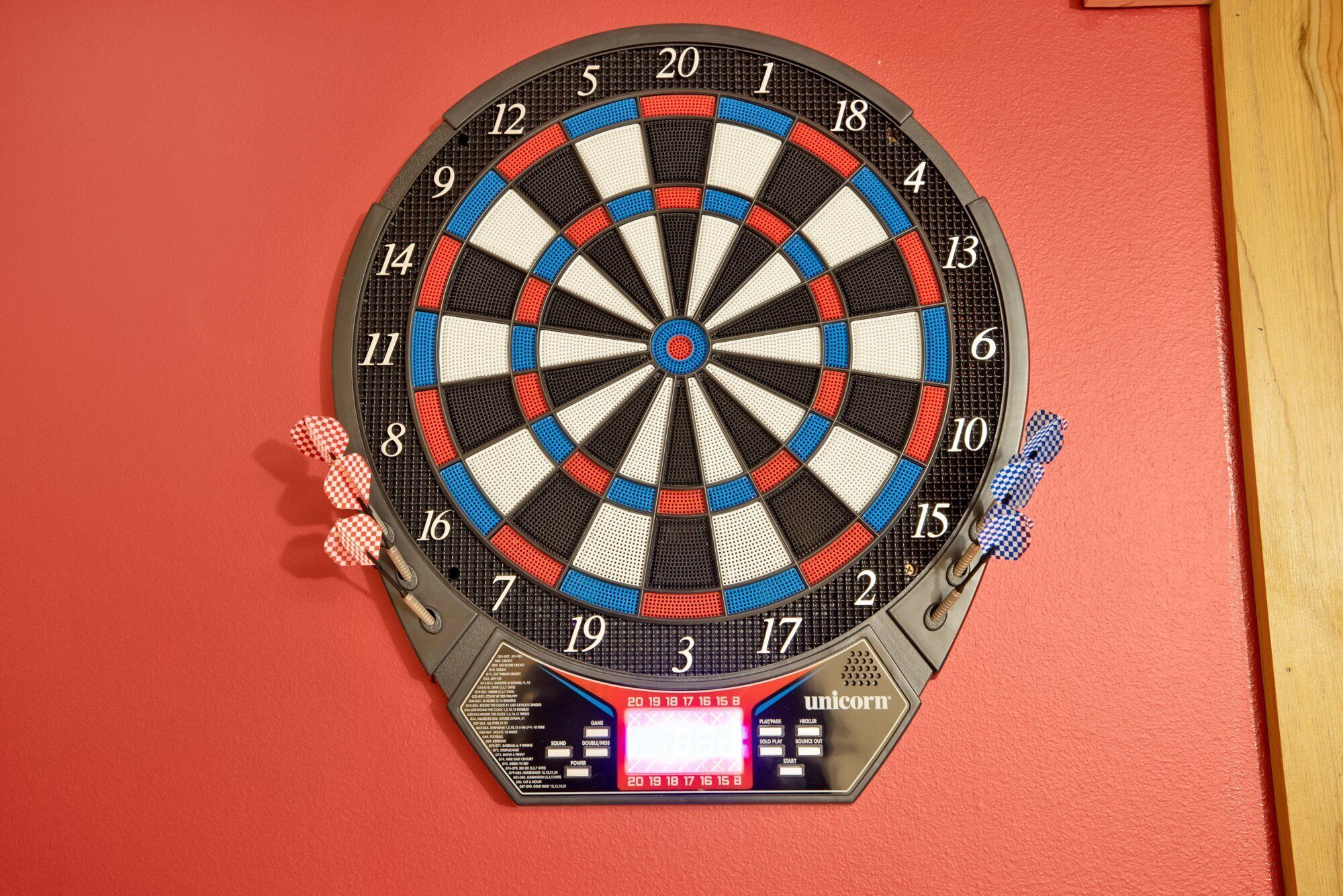 A dartboard mounted on a wall with a digital scoreboard below it.
