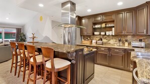 Una cucina moderna con piani in granito, elettrodomestici in acciaio inossidabile e mobili in legno.