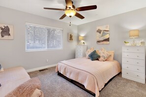 Un dormitorio con cama, cómoda, mesita de noche y ventilador de techo.