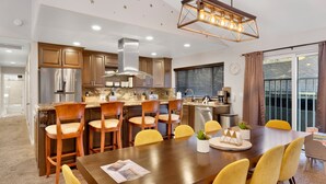 Una cucina moderna con elettrodomestici in acciaio inossidabile, un'isola centrale con posti a sedere a bancone e una zona pranzo con sedie gialle.