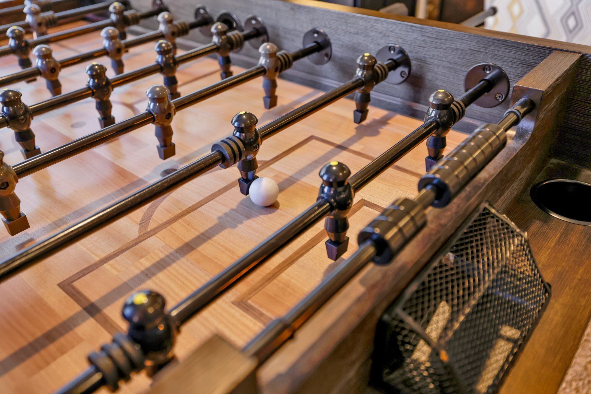 A foosball table with a wooden surface and metal rods.