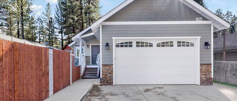A residential garage with a white door, a brick foundation, and a wooden fence.