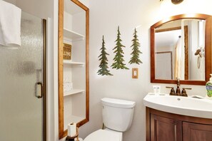 Bathroom features a toilet, sink, and mirror, with a cabinet and artificial pine tree decorations.