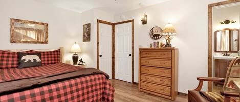 A bedroom with a bed, a dresser, a chair, a ceiling fan, and a wall-mounted lamp.
