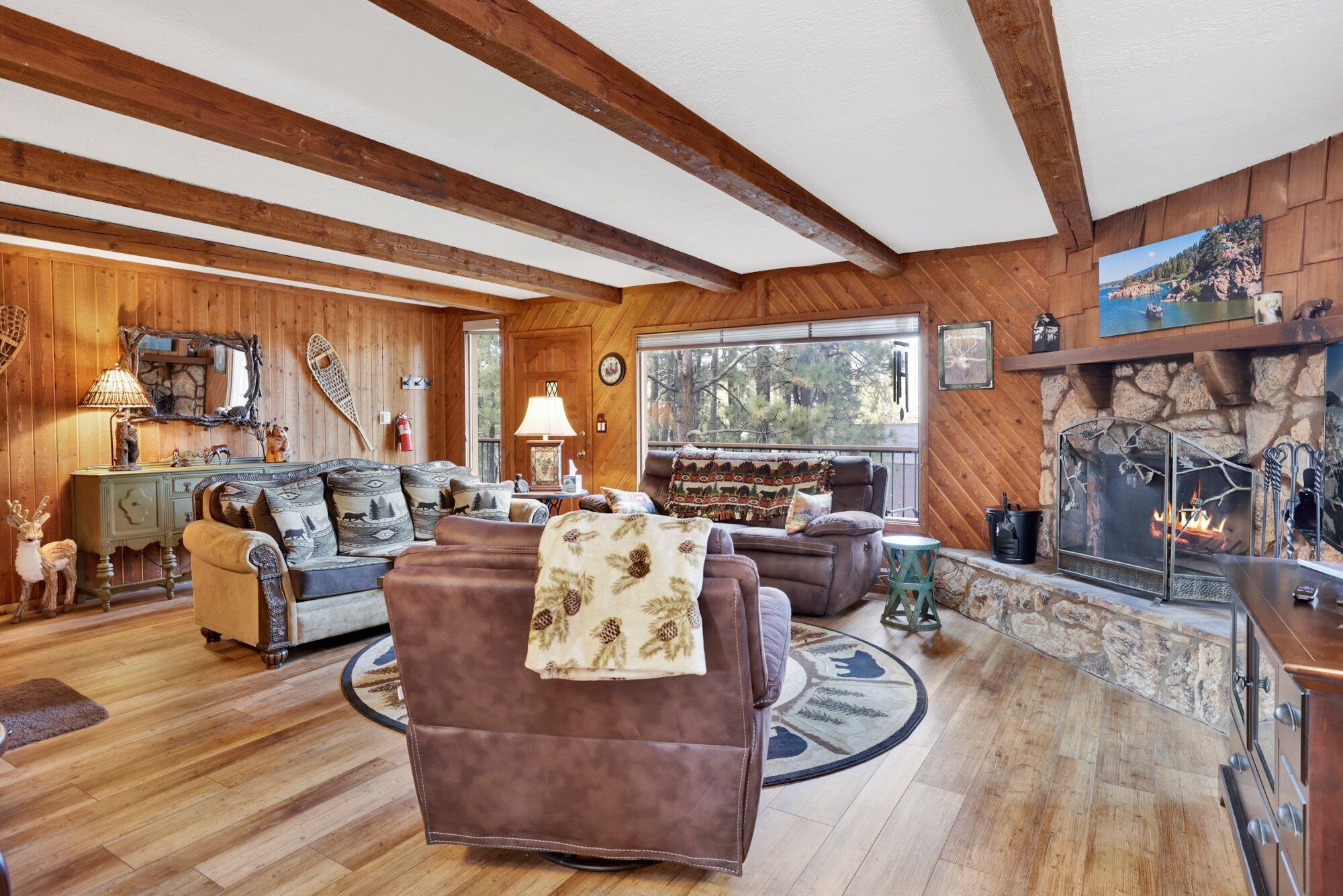Ein gemütliches Wohnzimmer mit Holzwänden und einem Kamin aus Stein. Zwei Sofas und ein Couchtisch sind vorhanden.