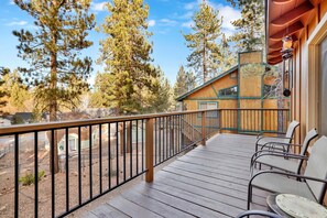 Enjoy a serene forest view from this deck, which offers comfortable seating and a small table.