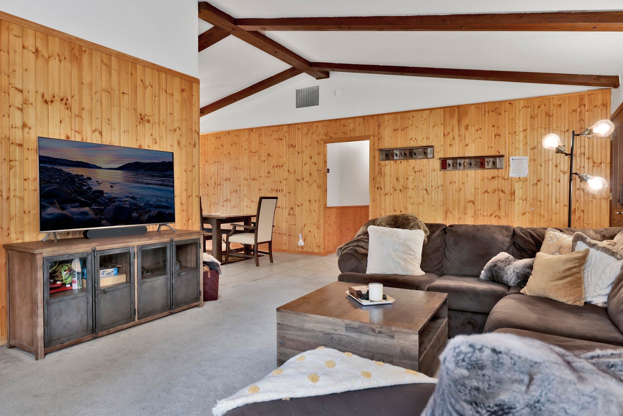A cozy living room with wooden walls, a flat-screen TV, a sofa, and a coffee table.