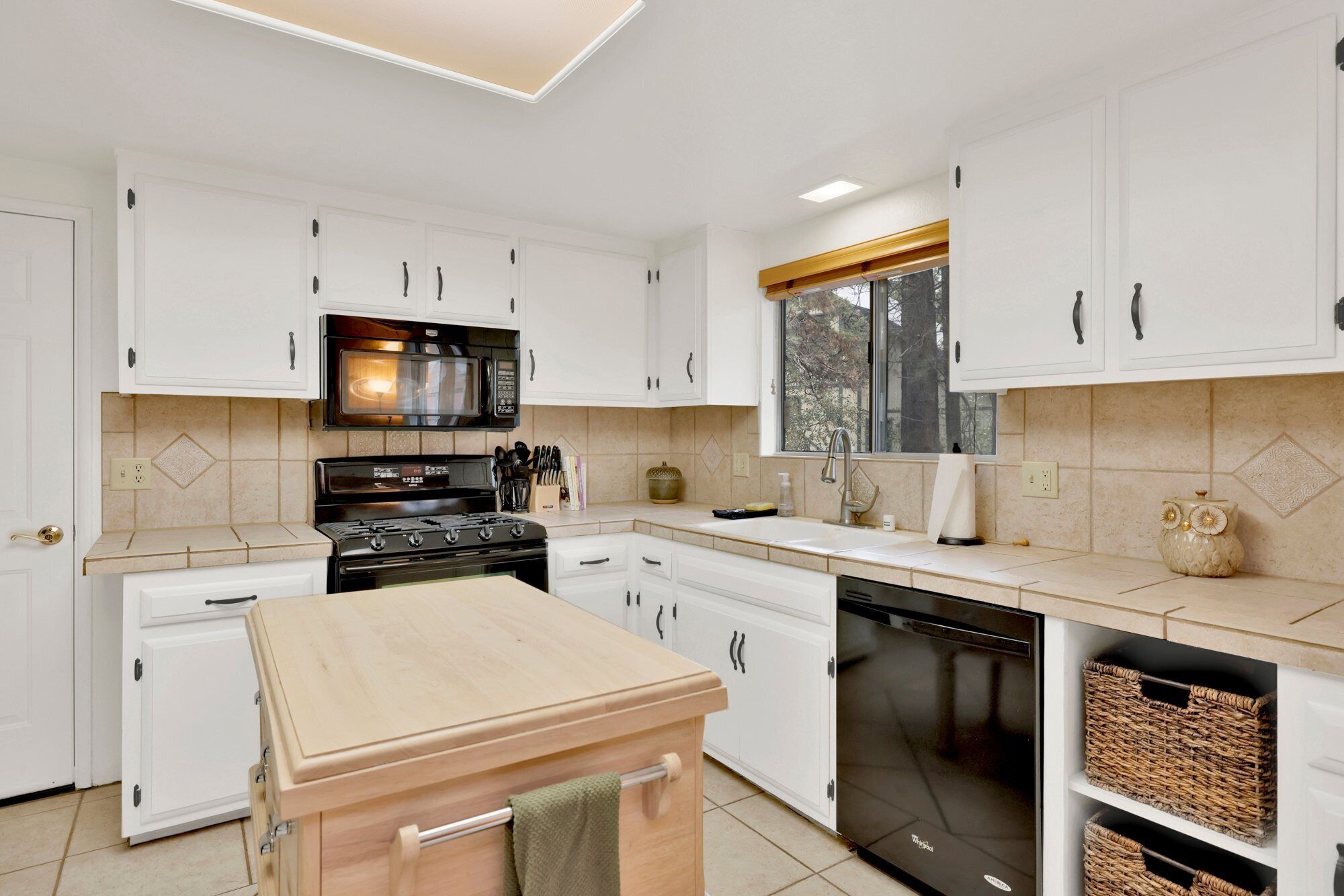 A modern kitchen with white cabinets, a black stove, a microwave, and a dishwasher.
