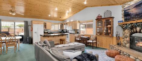 A cozy cabin interior with a living room, kitchen, and fireplace.