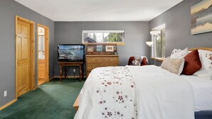 A bedroom with a bed, a dresser, a TV, and a window.