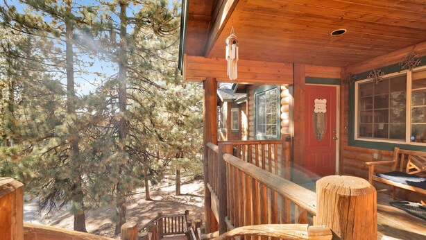 A wooden cabin with a porch, a welcome sign, and a birdhouse.