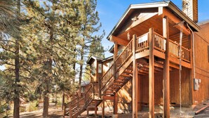 A wooden cabin with a wooden staircase leading to a balcony.