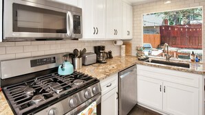 A modern kitchen with white cabinets, a stainless steel microwave, a gas stove, and a dishwasher. - Maltby Modern LOG Cabin #2307 (Big Bear City)