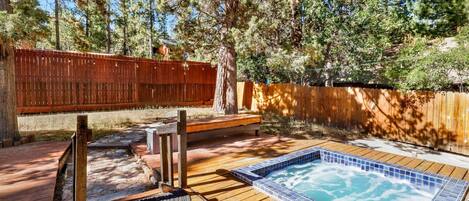 A wooden deck with a hot tub, a wooden bench, and a wooden fence.