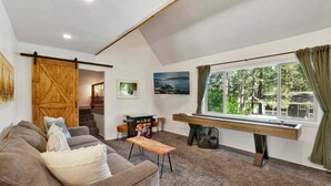 Un salon confortable avec un canapé, un bureau en bois, une fenêtre avec des rideaux et un escalier menant à une autre pièce.