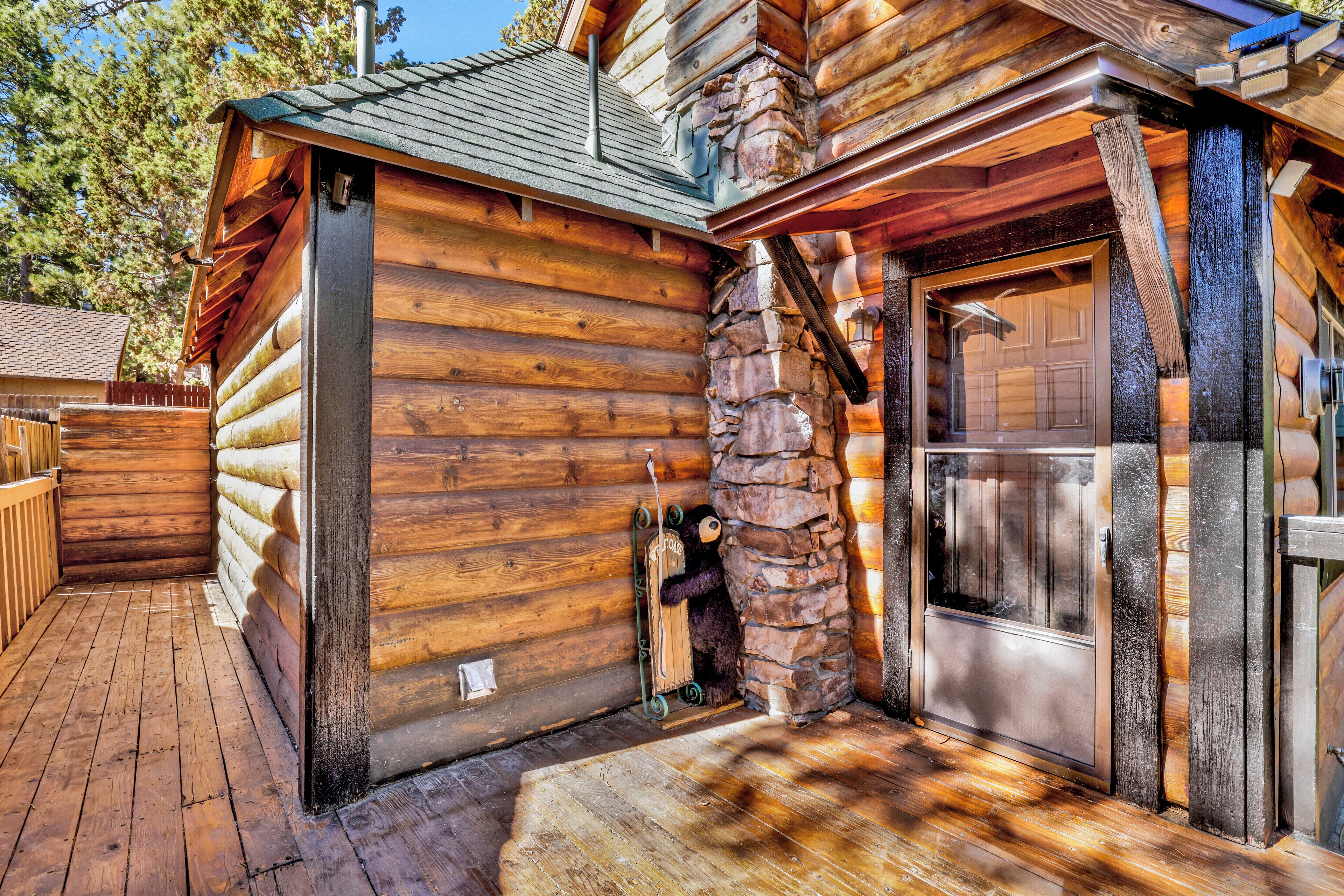 Une cabane en rondins avec une cheminée en pierre, un revêtement extérieur en bois et une porte en métal.