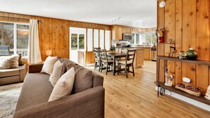 Ein geräumiges Wohnzimmer mit einer großen Couch und einem Essbereich mit Holztischen und -stühlen.
