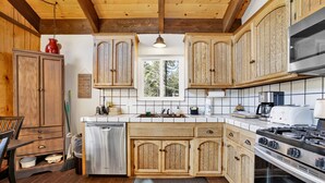 A kitchen with wooden cabinets, a stainless steel dishwasher, a stove, and a window providing natural light.
