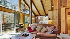 A cozy living room with a brown leather sofa, a wooden coffee table, and a dining area with a small table and chairs.